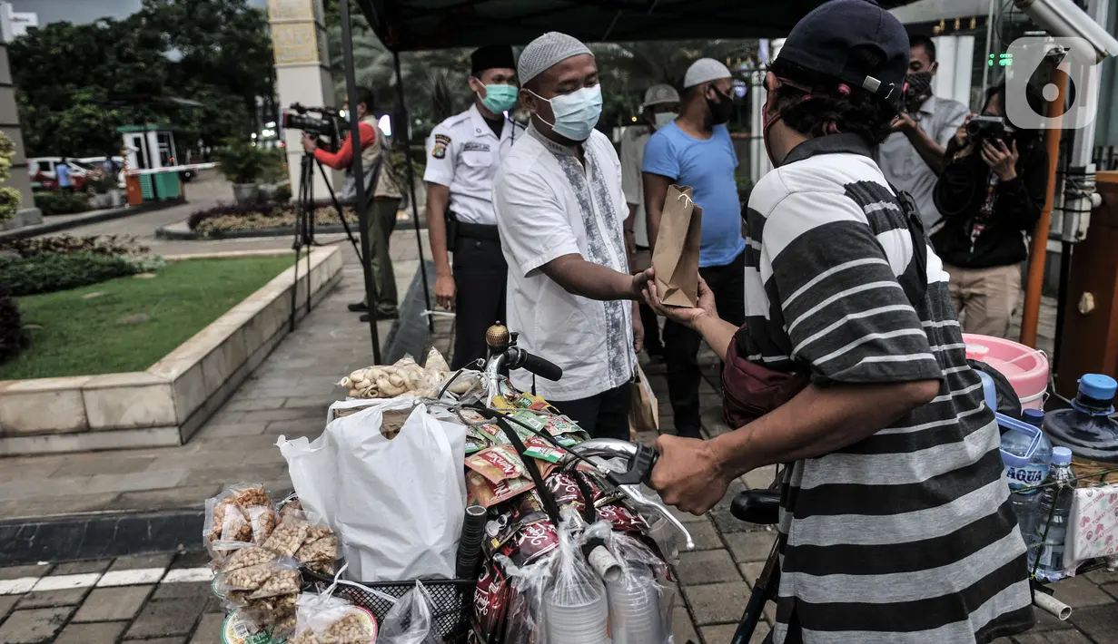 Petugas membagikan takjil kepada pedagang keliling secara drive thru di Kompleks Masjid Al-Azhar, Jakarta, Selasa (13/4/2021). Pengelola Masjid Al-Azhar menyiapkan 500 bungkus takjil per hari yang dibagikan secara drive thru guna mencegah penyebaran COVID-19. (merdeka.com/Iqbal S. Nugroho)