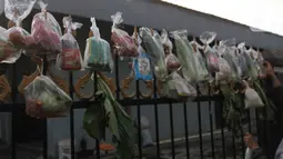 Sejumlah sayuran, beras, dan bumbu masak secara gratis yang digantung pada pagar rumah di Gang Palautan, Cilodong, Depok, Jumat (21/1/2022). Warga Rt 04 Rw 01 di kawasan tersebut secara swadaya berbagi setiap hari Jumat kepada warga yang terdampak pandemi COVID-19. (Liputan6.com/Herman Zakharia)