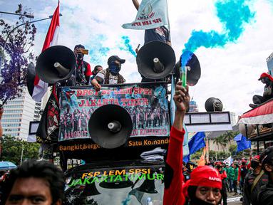Massa buruh menyalakan asap suar saat unjuk rasa di Patung Kuda, Jakarta, Kamis (22/10/2020). Aksi gabungan buruh, petani, mahasiswa, dan pelajar dilakukan untuk menyuarakan penolakan pengesahan UU Cipta Kerja dan meminta Presiden mengeluarkan Perppu. (Liputan6.com/Faizal Fanani)
