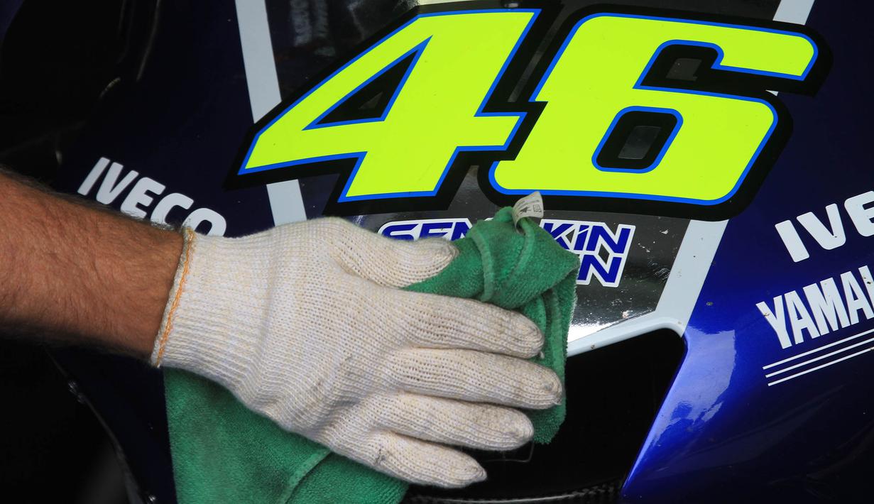 Pekerja membersihkan motor milik pebalap MotoGP asal Itali, Valentino Rossi. Bersama Yamaha, juara dunia sembilan kali itu menggunakan motor dengan dominasi warna biru. (AFP Photo/Radek Mica)