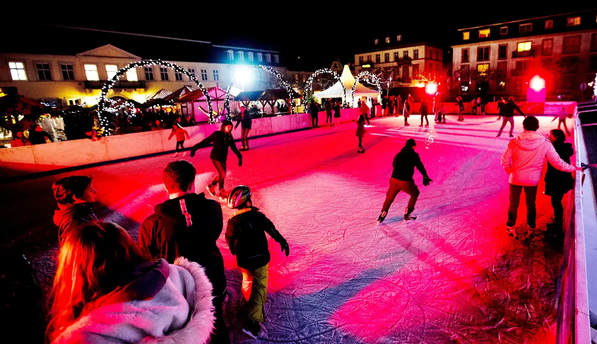 Pengunjung bermain di arena es yang ada di pasar Natal tradisional Kota Tua Heidelberg, Jerman, Selasa (4/12). Pasar Natal tradisional ini terletak di bawah kastil terkenal. (AP Photo/Michael Probst).
