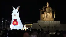 Lentera raksasa yang bersinar di sebelah patung Raja Sejong dari Dinasti Joseon selama perayaan Tahun Kelinci 2023 mendatang di Lapangan Gwanghwamun, Seoul, Korea Selatan, Senin (19/12/2022). Festival Lentera ini akan berlangsung dari 19-31 Desember 2022. (AP Photo/Ahn Young-joon)