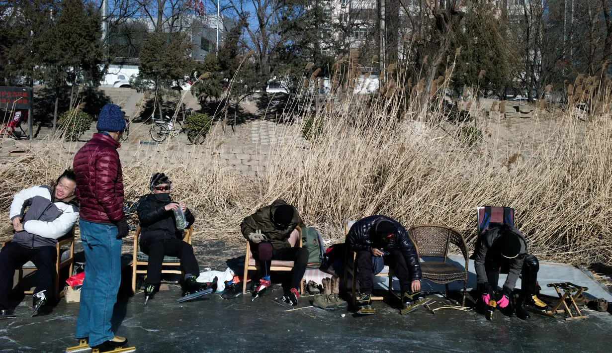 Sejumlah warga bersiap bermain ice skating di sungai yang membeku di Beijing, China (21/1). Akibat membeku, Sungai ini menjadi objek wisata dadakan yang banyak diminati wisatawan. (AFP/Fred Dufour)