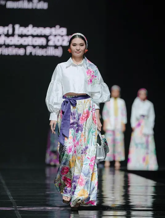 Christine Priscilla tampil manis dengan cropped puffy sleeve shirt dan rok panajng bermotif bunga. Ia melengkapi tampilannya dengan belt biru dan bandana [@officialputeriindonesia]