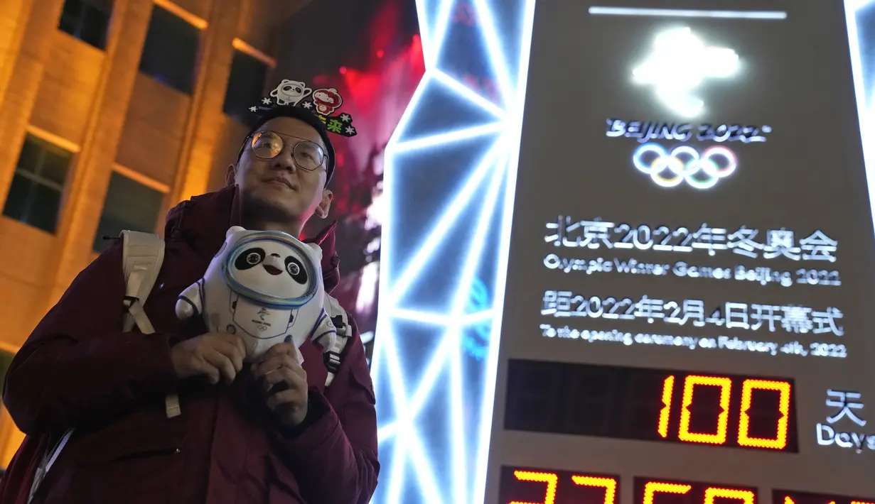 Seorang pendukung Olimpiade Musim Dingin Beijing 2022 berpose dengan jam hitung mundur 100 hari menuju pembukaan Olimpiade Musim Dingin Beijing 2022, di Beijing, China, Selasa (26/10/2021). Olimpiade Musim Dingin Beijing 2022 akan berlangsung 4 hingga 20 Februari. (AP Photo/Ng Han Guan)