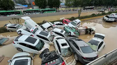 Mobil-mobil terendam banjir setelah hujan lebat melanda kota Zhengzhou di provinsi Henan tengah China (21/7/2021). Luapan sungai menggenangi jalan-jalan dan membuat kendaraan terbawa arus setelah curah hujan 200 mm turun dalam satu jam. (AFP/STR)