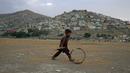 Seorang bocah Afghanistan mendorong roda saat terjadi badai pasir di pinggiran Kabul, Afghanistan (25/8/2020). Sebuah badai pasir hebat melanda Kabul. Badai menyebabkan jarak pandang jadi berkurang. (AP Photo / Rahmat Gul)