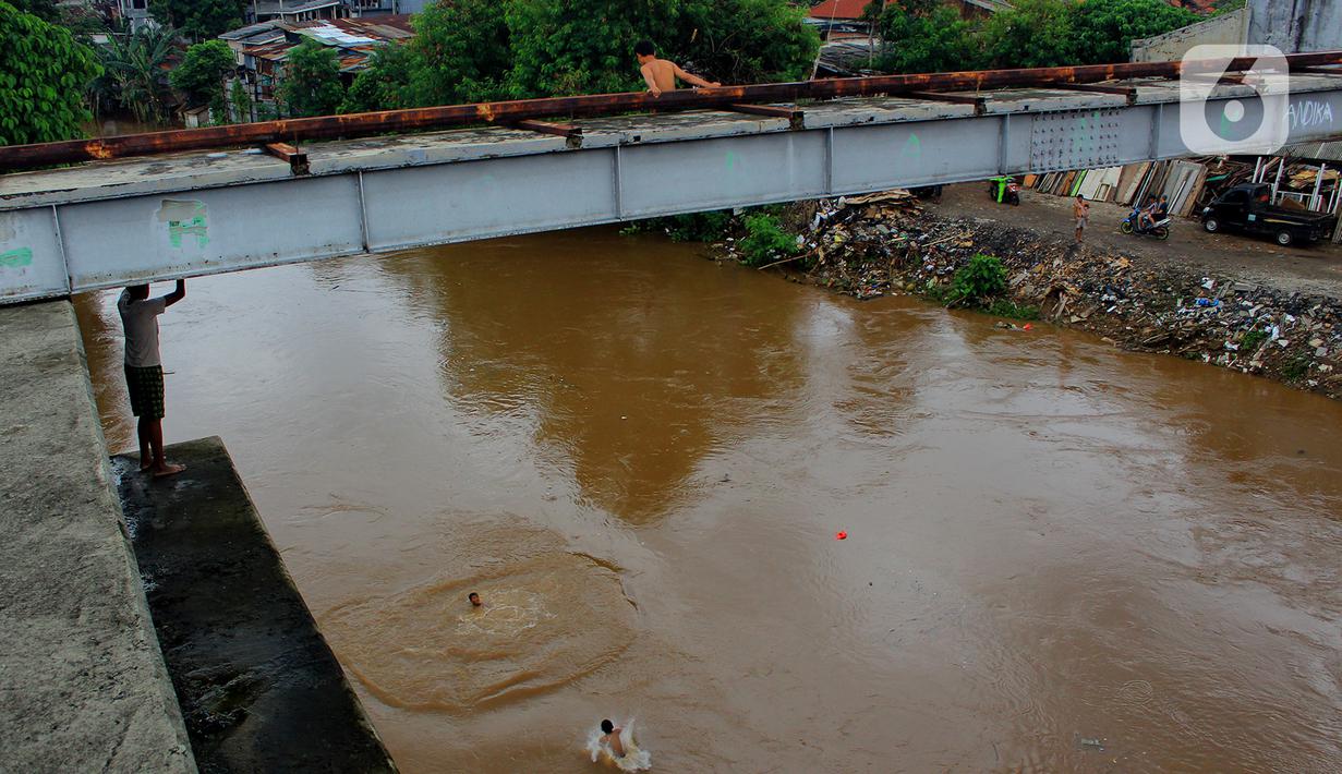 Seorang anak bersiap melompat dari jembatan ke Kali Ciliwung Kalibata, Jakarta, Selasa (25/2/2020). Kali Ciliwung meluap usai hujan deras mengguyur Jakarta dan sekitarnya pada kemarin malam. (merdeka.com/magang/Muhammad Fayyadh)