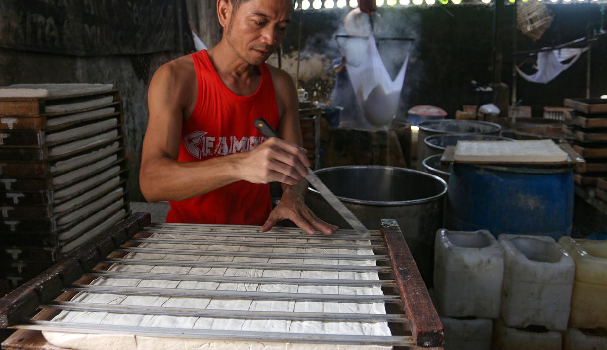 Data dari Dinas Ketahanan Pangan Kelautan dan Pertanian DKI Jakarta menunjukkan harga kedelai di tingkat pengrajin berada pada kisaran Rp 10.500 hingga Rp 11.000 per kilogram, naik dari sebelumnya Rp 8.000 hingga Rp 8.600 per kilogram. Tampak dalam foto, perajin menyelesaikan pembuatan tahu di Duren Tiga Jakarta Selatan, Selasa 14 April 2026, di tengah kenaikan harga kedelai yang berdampak pada biaya produksi. (merdeka.com/Arie Basuki)