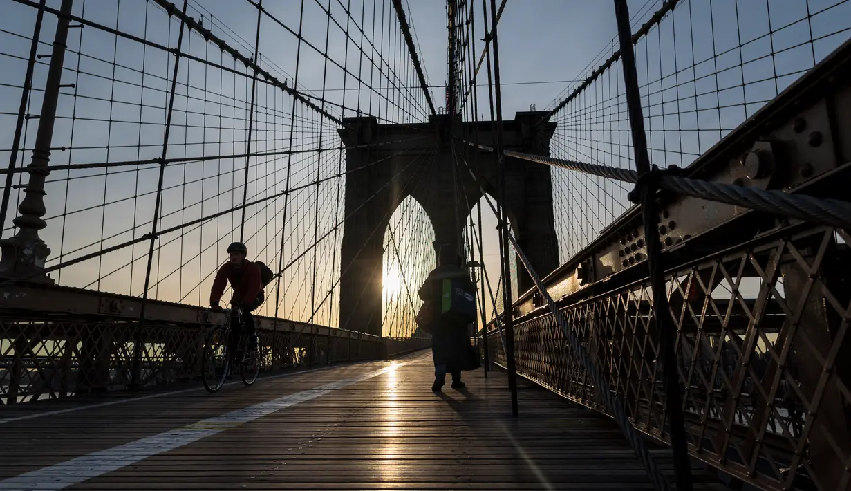 Pengendara sepeda menyeberangi Jembatan Brooklyn melintasi East River ke Manhattan di New York City, 7 Januari 2019. Brooklyn Bridge yang memiliki panjang 1.825 meter itu merupakan salah satu jembatan suspensi tertua di AS. (Johannes EISELE/AFP)