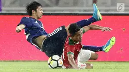 Dua pesepak bola Timnas Indonesia U-19 dan Jepang U-19 terjatuh saat berebut bola pada laga uji coba babak kedua di Stadion Utama GBK, Jakarta, Minggu (25/3). Timnas Indonesia menelan kekalahan 1-4 dari Jepang U-19. (Liputan6.com/Angga Yuniar)