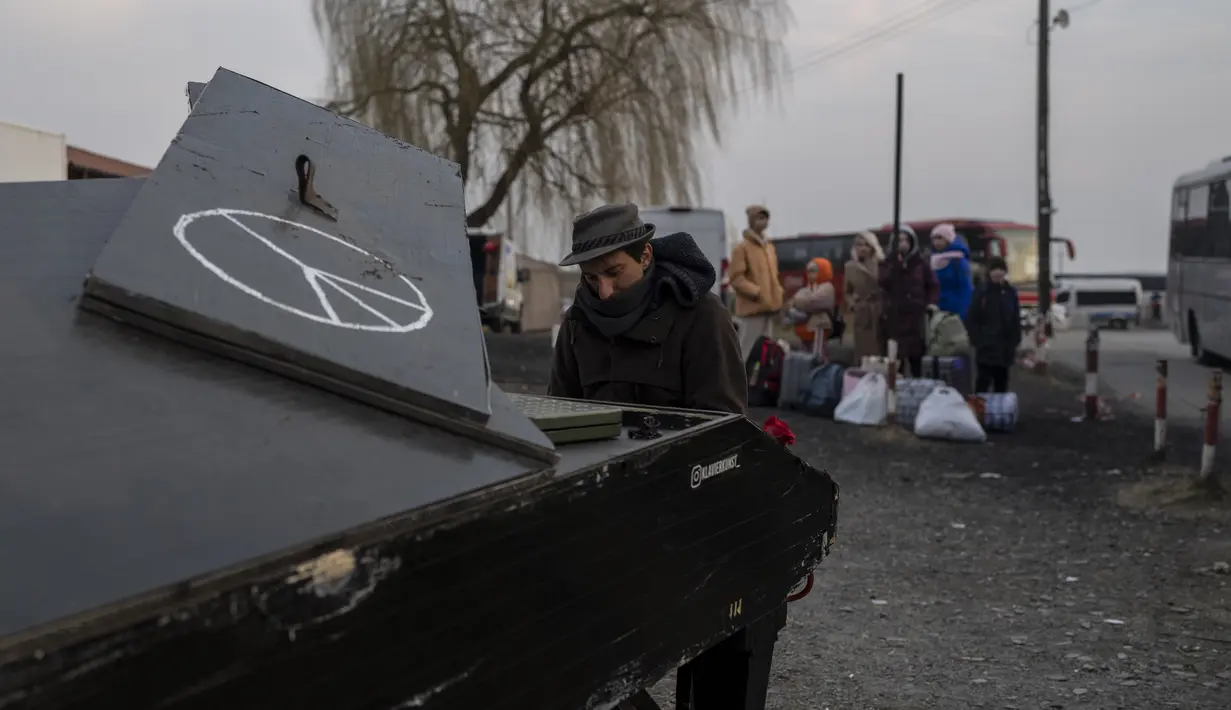 Pianis Jerman keturunan Italia Davide Martello, bermain piano di perbatasan di Medyka, Polandia, pada Rabu, 16 Maret 2022, untuk orang-orang yang melarikan diri dari perang dari Ukraina dalam latar belakang. (AP Photo/Petros Giannakouris)