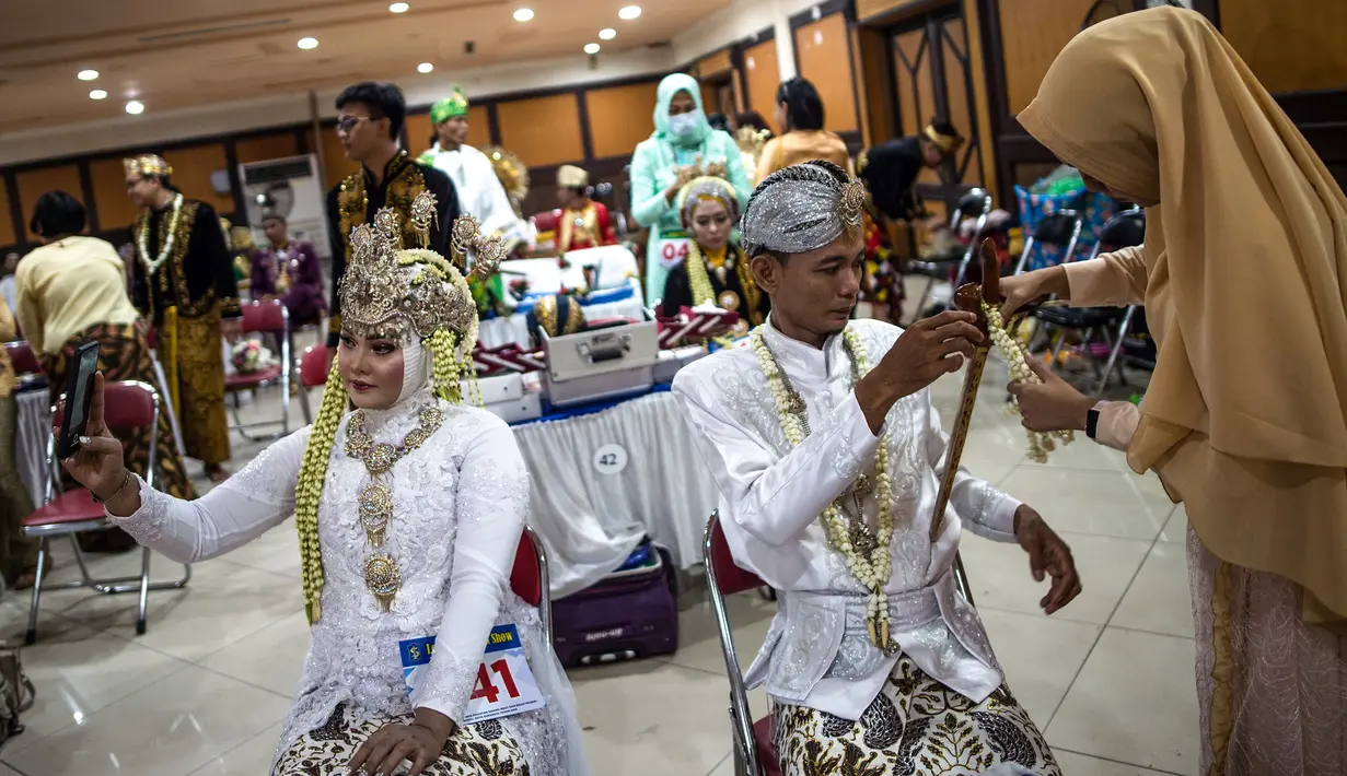 Pasangan pengantin bersiap mengikuti nikah massal di Surabaya, Jawa Timur, Rabu (18/12/2019). Sebanyak 60 pasangan pengantin mengikuti nikah massal yang digelar Dinas Sosial Kota Surabaya. (JUNI KRISWANTO/AFP)