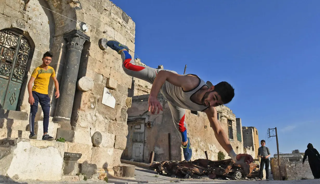 Dua pemuda berlatih parkour di Aleppo, Suriah, (7/4). Para pemuda memanfaatkan reruntuhan bangunan akibat perang menjadi tempat untuk melatih kelincahannya bermain Parkour. (AFP Photo/George Ourfalian)