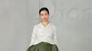 Yumi Kawai tampil dengan atasan putih lengan panjang bermotif dipadukan rok ruffle asimteris hijau bermotif. Artis Jepang ini juga membawa tas Dior warna beige dan mengenakan heels polkadot. [Dok. DIOR]