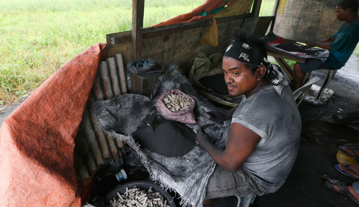 Pekerja memasukkan bubuk mesiu ke dalam sebuah tabung kecil saat membuat kembang api di sebuah gubuk, provinsi Bulacan, utara Manila, Rabu (27/12). Warga Filipina menyiapkan kembang api untuk menyambut tahun baru 2018. (AP/Bullit Marquez)