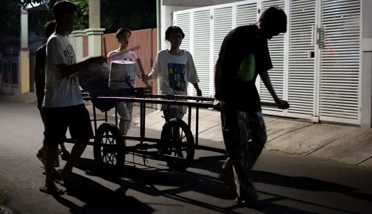 Foto yang diambil pada 19 Mei 2018, para pemuda bernyanyi dan memukul drum berkeliling sekitar lingkungan mereka di Jakarta. Kegiatan tersebut merupakan tradisi selama bulan ramadan membangunkan warga untuk sahur. (AFP PHOTO/BAY ISMOYO)