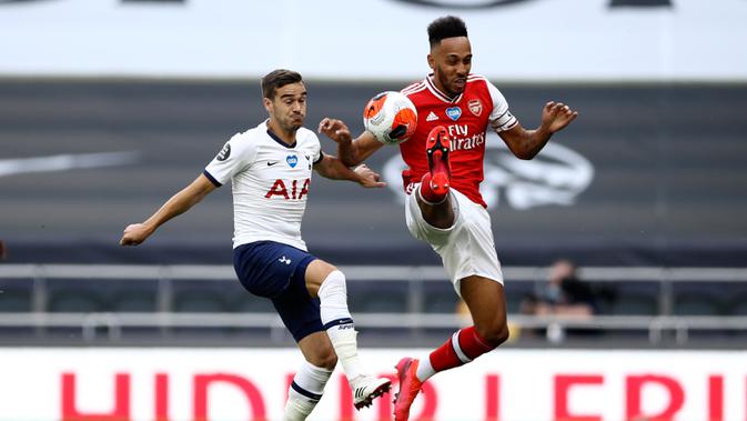Penyerang Arsenal, Pierre-Emerick Aubameyang berebut bola dengan bek Tottenham Hotspur, Harry Winks pada pertandingan lanjutan Liga Inggris di Stadion Tottenham Hotspur di London, Inggris, Minggu (12/7/2020). Tottenham menang tipis atas Arsenal 2-1. (Tim Goode/Pool via AP)