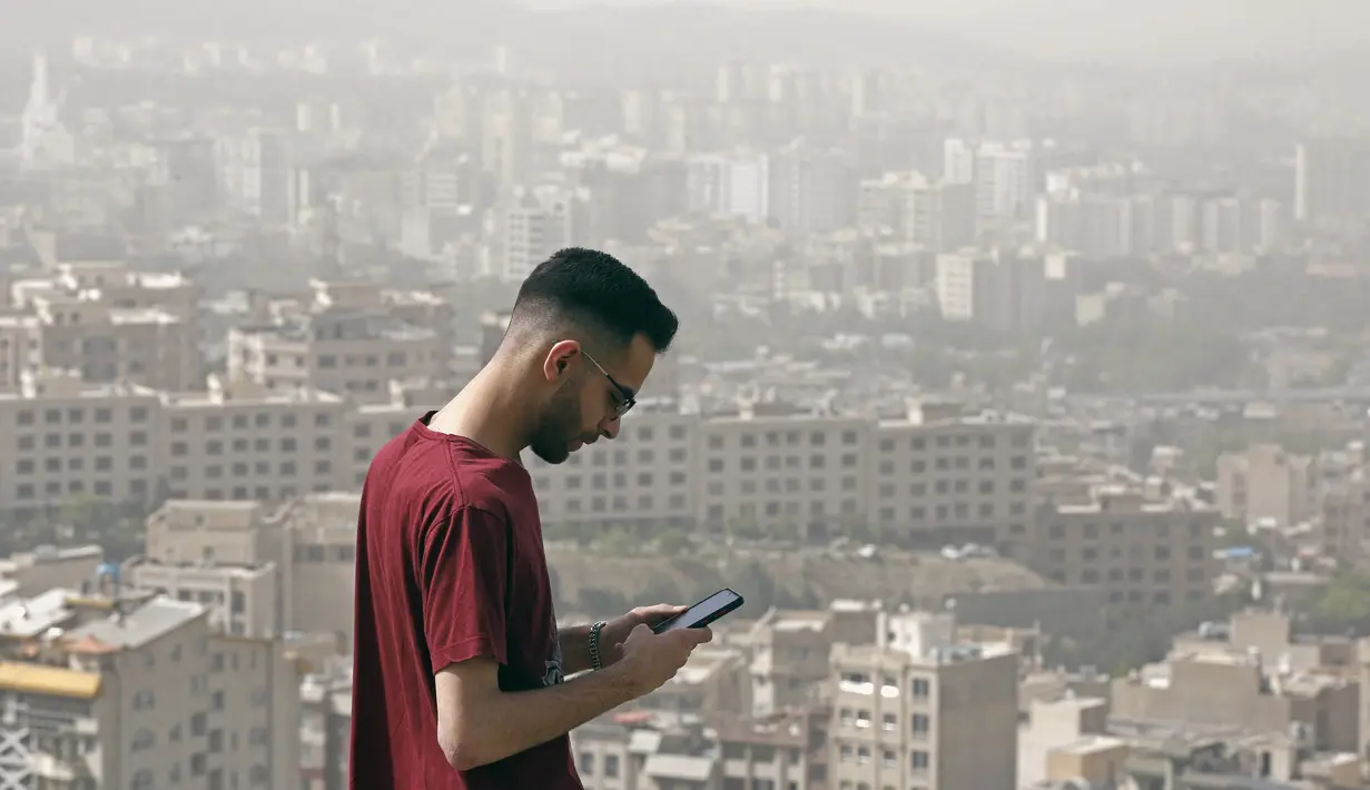 <p>Seorang pria berdiri di atas bukit selama badai pasir hebat yang melanda utara ibu kota Iran, Teheran pada 17 Mei 2022. Kantor-kantor pemerintah, serta sekolah dan universitas diumumkan ditutup di banyak provinsi di Iran karena kondisi "cuaca tidak sehat" dan badai pasir yang menyelimuti, menurut laporan media pemerintah. (AFP)</p>