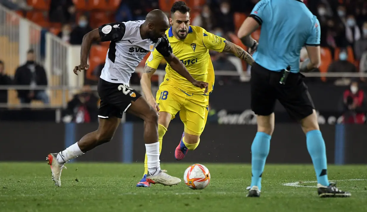 Bek Valencia Prancis Dimitri Foulquier (kiri) membawa bola dari kejaran pemain Cadiz, Alvaro Negredo selama pertandingan perempat final Piala Raja atau Copa del Rey di stadion Mestalla di Valencia 3/2/2022). Valencia menang tipis atas Cadiz 2-1 dan melaju ke semifinal. (AFP/Jose Jordan)