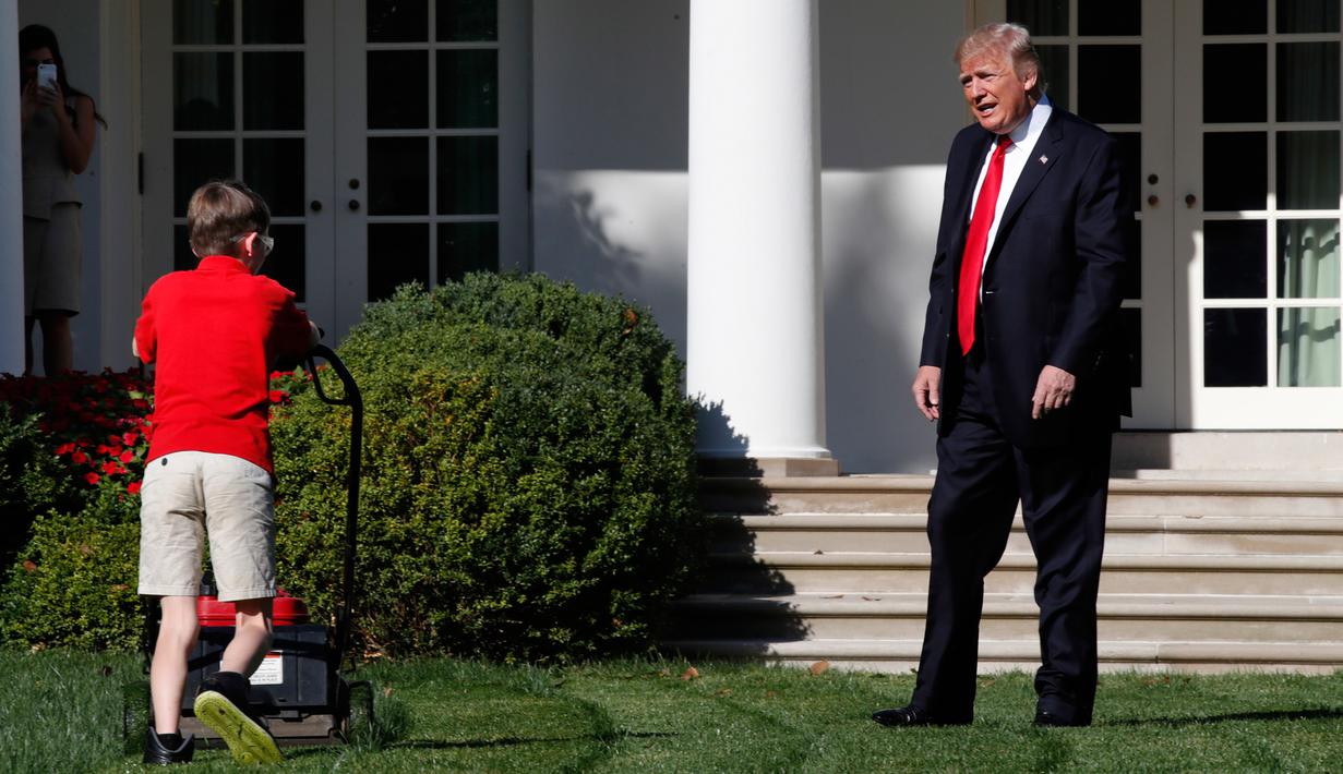 Presiden AS, Donald Trump menyapa anak laki-laki, Frank Giaccio yang tengah mendorong mesin pemotong rumput di Rose Garden, Gedung Putih, Jumat (15/9). Bocah 11 tahun itu berada di Rose Garden setelah menulis surat kepada Trump. (AP/Jacquelyn Martin)