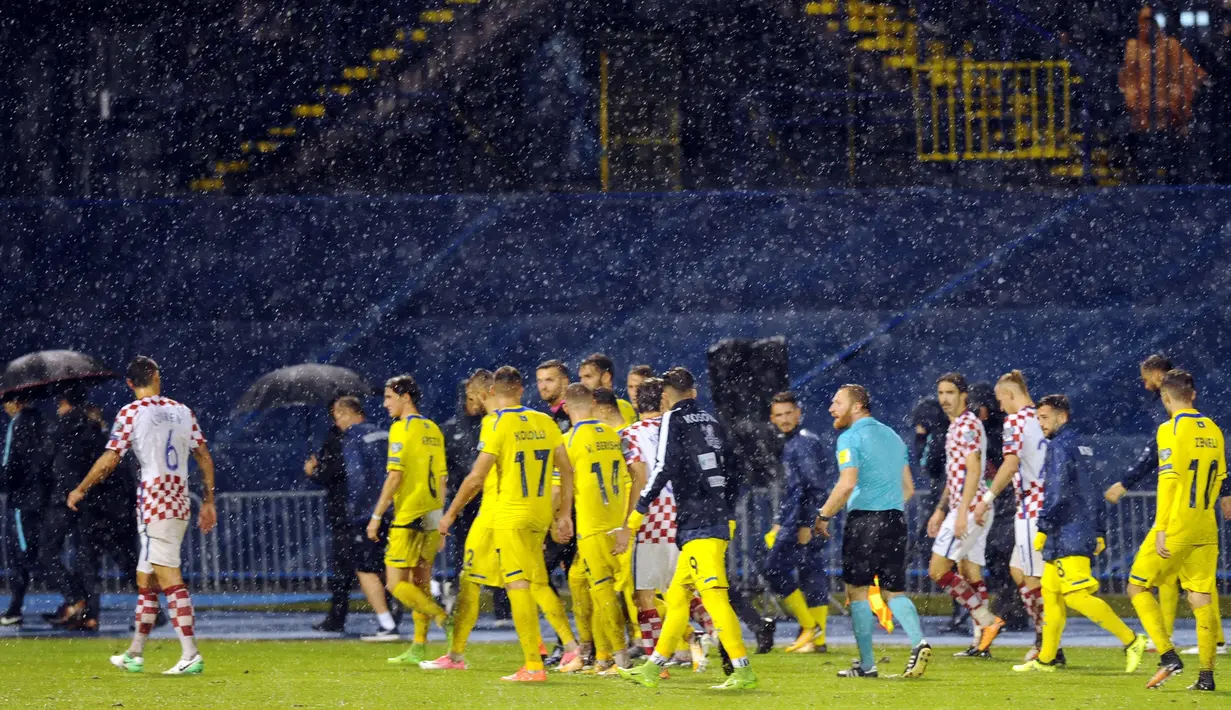 Para pemain Kroasia dan Kosovo menuju ruang saat hujan deras pada laga Grup I kualifikasi Piala Dunia 2018 di Stadion Maksimir, Zagreb, (2/9/2017).  Laga tersebut diberhentikan wasit karena stadion penuh genangan air. (AFP/ STR)