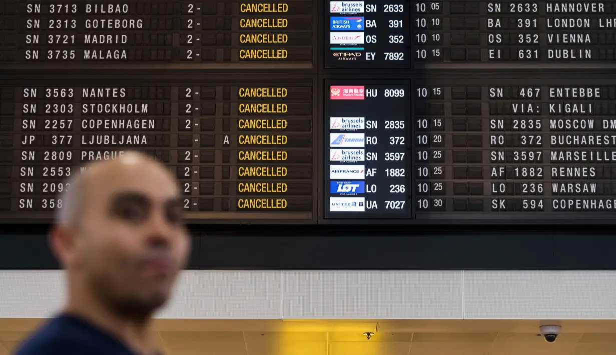 Penumpang berjalan melewati layar informasi keberangakatan di Bandara Brussels, Zaventem, Belgia, Rabu (13/2). Penerbangan pemerintah dan militer tidak terpengaruh dengan adanya mogok nasional. (AP Photo/Geert Vanden Wijngaert)