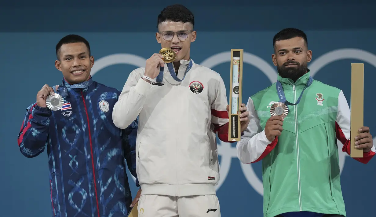 Para peraih medali kelas 73 kg putra cabor angkat besi Olimpiade Paris 2024 (dari kiri) Weeraphon Wichuma (perak/Thailand), Rizki Juniansyah (emas/Indonesia) dan Dimitrov Bozhidar Andreev (perunggu/Bulgaria) berfoto di atas podium usai upacara penyerahan medali di Paris Expo Porte de Versailles, Paris, Kamis (8/8/2024). (AP Photo/Kin Cheung)