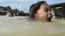 Anak-anak berenang saat banjir melanda kawasan Rantau Panjang, Malaysia, Kamis (5/1). Sekitar 23 ribu orang terpaksa mengungsi karena banjir yang disebabkan hujan muson ini. (AFP PHOTO / MOHD RASFAN)