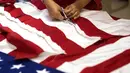 Seorang pekerja menyelesaikan pembuatan Bendera Amerika Serikat yang akan digunakan untuk upacara pelantikan presiden baru Amerika Serikat Donald Trump, Alexandria Virginia, AS (10/1). (AFP/Andrew Caballero Reynolds)