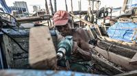 Syamsudin (71) saat menyelesaikan perbaikan kapal nelayan di kawasan Sunda Kelapa, Jakarta, Rabu (17/3/2021). Dalam membuat atau memperbaiki kapal, Syamsudin bekerja hanya seorang diri dengan mengandalkan keahliannya yang dimulai sejak pagi hingga sore hari. (merdeka.com/Iqbal S. Nugroho)