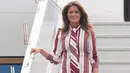 Ibu Negara AS, Melania Trump turun dari pesawat setibanya di Bandara Kotoka di Accra, Ghana, Selasa (2/10). Melania tampil modis dalam balutan shirt dress Celine dengan motif bergaris warna merah anggur, seharga sekitar Rp 30 juta. (AFP/SAUL LOEB)