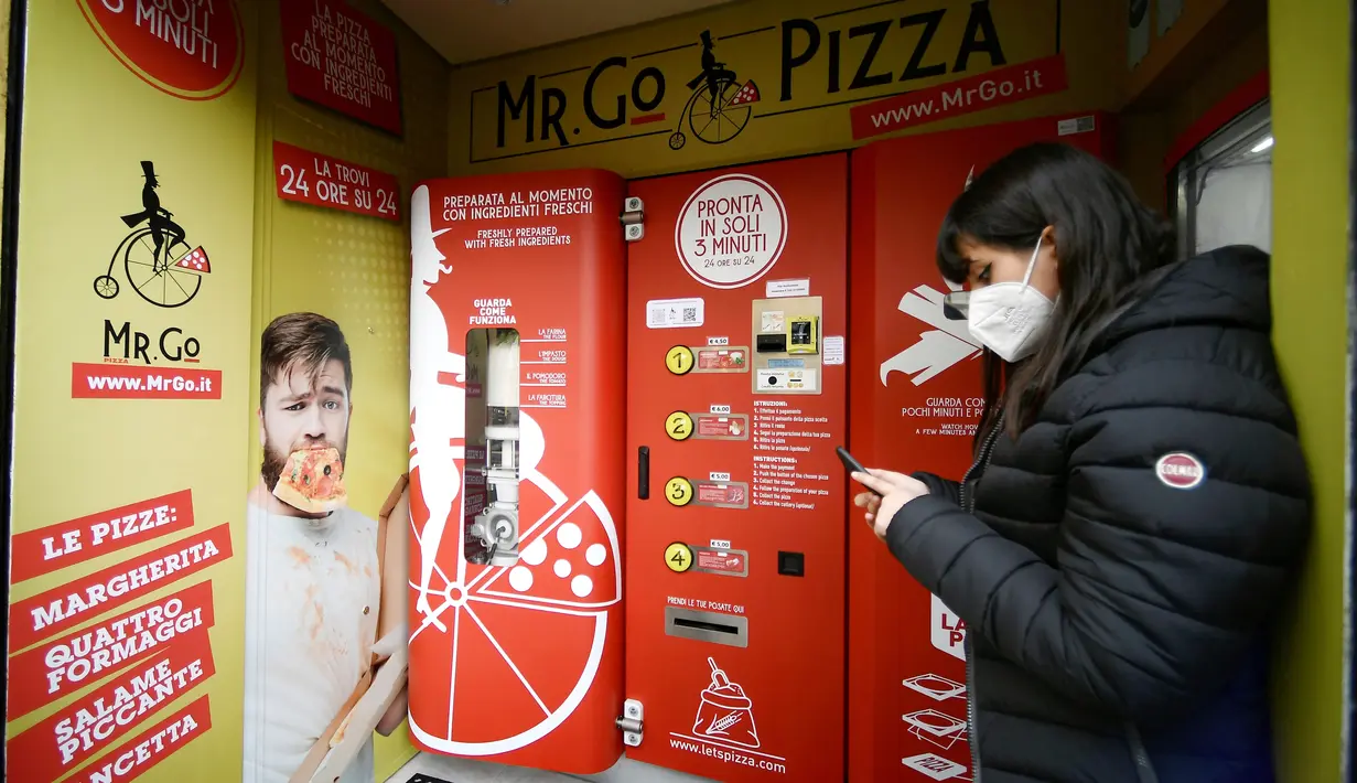 Seorang wanita menunggu pesanannya di mesin penjual pizza otomatis, yang pertama dari jenisnya di pusat kota Roma, pada 29 April 2021. Mesin penjual otomatis ini mampu menguleni adonan, membumbui, memasak, dan menyajikan pizza dalam kotak karton hanya dalam waktu tiga menit. (Filippo MONTEFORTE/AFP)
