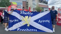 Suporter Skotlandia membentangkan bendera bertuliskan "Tartan Army" di area fanzone Gillette Stadium, Foxborough, Amerika Serikat, Jumat (19/6/2026), menjelang laga melawan Maroko pada Piala Dunia 2026. Bendera tersebut menjadi simbol kebanggaan dan dukungan Tartan Army kepada Timnas Skotlandia. (KLY Sports/Hery Kurniawan)