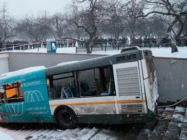 Sejumlah orang melihat lokasi sebuah bus yang hilang kendali dan masuk ke dalam tangga menuju jalan bawah tanah di Moskow, Rusia, Senin (25/12). Bus menerobos underpass yang sedang dilalui banyak pejalan kaki hingga menewaskan 4 orang (AP/Ivan Sekretarev)
