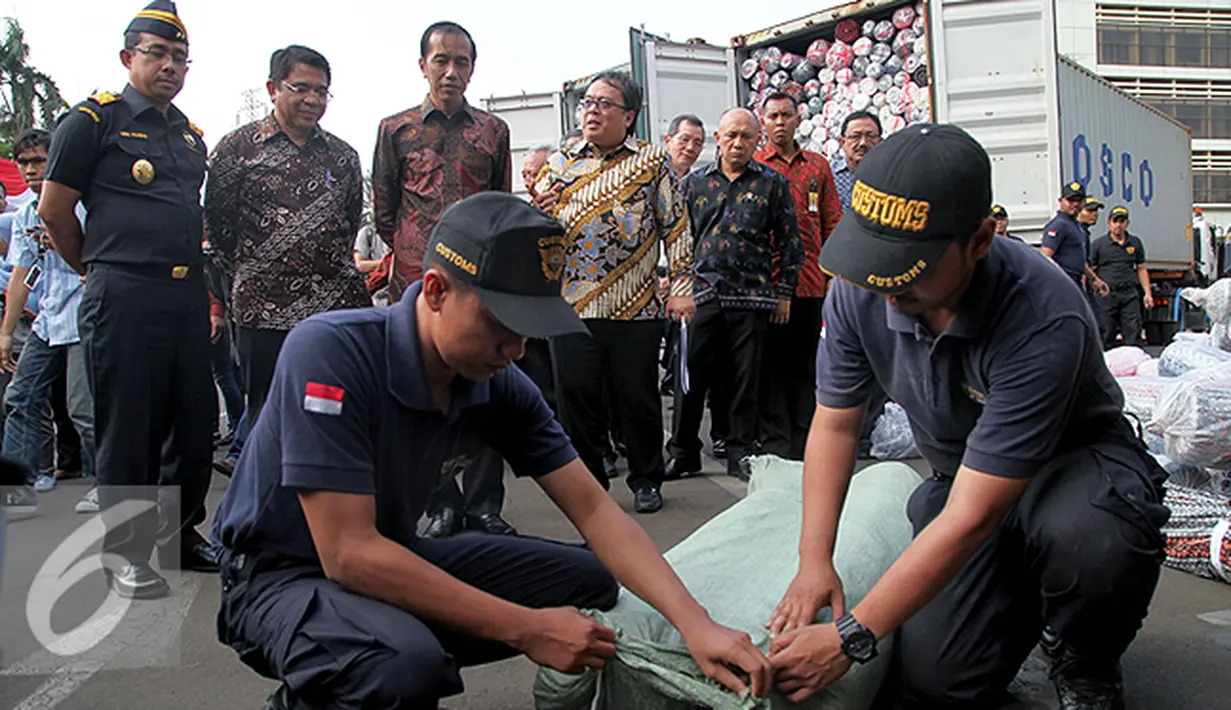 Presiden Joko Widodo melihat petugas membuka barang tekstil impor ilegal di Direktorat Jenderal Bea dan Cukai, Jakarta, Jumat (16/10/2015). Jokowi menyebut, maraknya impor tekstil ilegal merusak industri nasional. (Liputan6.com/Faizal Fanani)