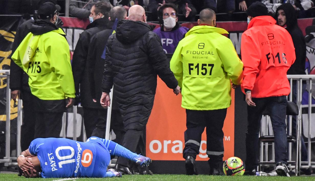 Pemain Olympique de Marseille Dimitri Payet jatuh setelah terkena botol air yang dilemparkan oleh seorang suporter, di Stadion Groupama, Lyon, Prancis, Minggu (21/11/2021). (AFP/Philippe Desmazes)