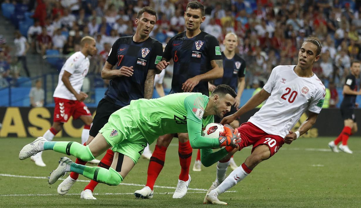 Kiper Kroasia, Danijel Subasic mengamankan bola dari kejaran pemain Denmark, Yussuf Yurary Poulsen pada laga 16 besar Piala Dunia 2018 di Nizhny Novgorod Stadium, Rusia, (1/7/2018). Kroasia menang 3-2 lewat adu penalti. (AP/Darko Bandic)