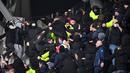 Petugas keamanan turun tangan di tribun penonton ketika para pendukung bentrok pada pertandingan 64 besar Piala Prancis antara Paris FC dan Olympique Lyon di stadion Charlety, Paris,  Jumat (17/12/2021). Laga pun dibatalkan menyusul kerusuhan penonton tersebut. (Bertrand GUAY/AFP)