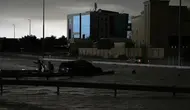 Para pria memberi isyarat ketika mereka mencoba menarik kendaraan keluar dari banjir di Dubai, Uni Emirat Arab, Selasa 16 April 2024. (Jon Gambrell/AP)