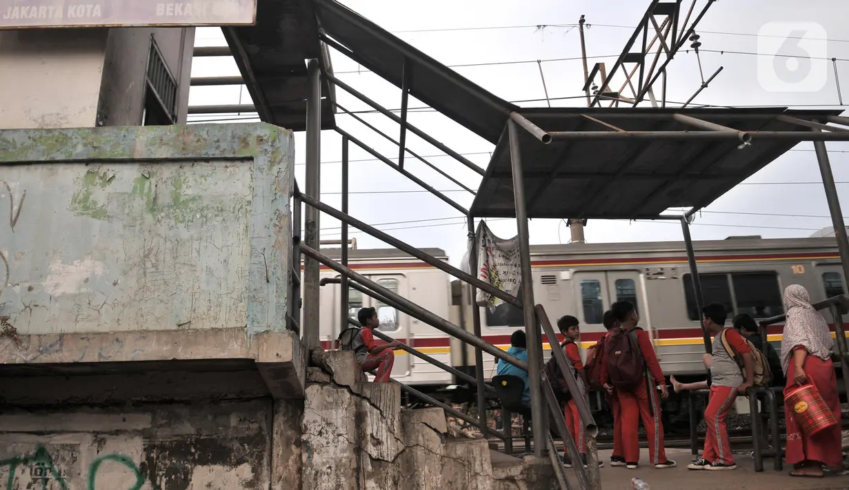 Sejumlah anak menunggu kereta melintas saat hendak menyeberangi rel Stasiun Buaran lama, Jakarta, Selasa (8/10/2019). Stasiun Buaran lama sudah tidak difungsikan sejak November 2018 akibat adanya Stasiun Buara baru. (merdeka.com/Iqbal Nugroho)