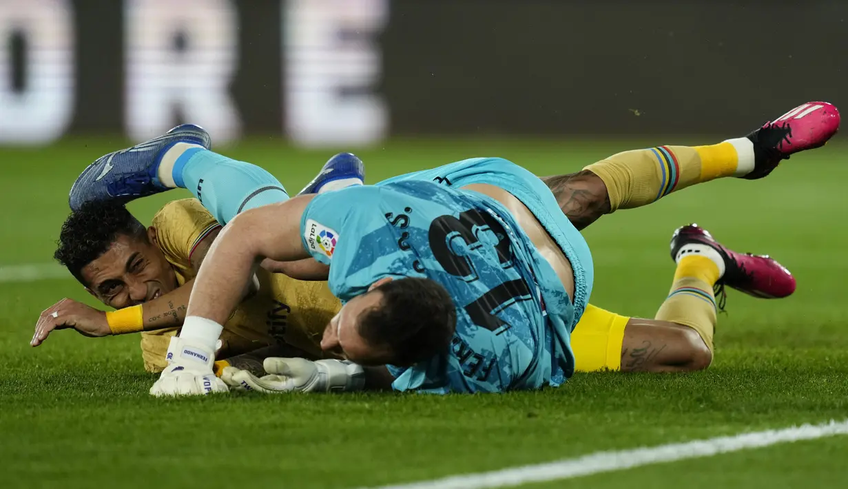 Penyerang Barcelona Raphinha bertubrukan dengan kiper Almeria Fernando pada pekan ke-23 Liga Spanyol di Power Horse Stadium, Senin dini hari WIB (27/2/2023). Kemenangan ini mengantarkan Almeria keluar dari zona degradasi ke posisi 15 dengan koleksi 25 poin. (AP Photo/Jose Breton)