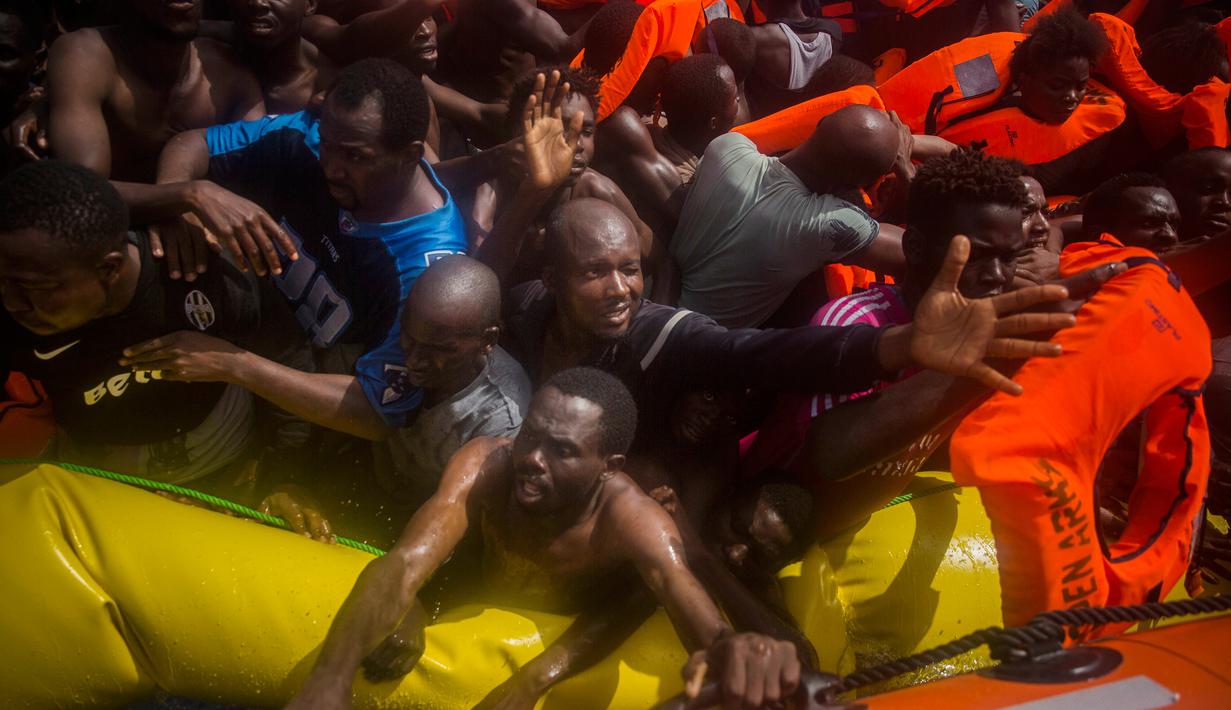 Imigran Afrika meminta jaket pelampung saat diselamatkan oleh kapal bermisi kemanusiaan milik LSM Spanyol di tengah Laut Mediterania, lepas pantai Libya, Selasa (25/7). Petugas menemukan 13 jasad di atas perahu karet padat imigran itu. (AP/Santi Palacios)