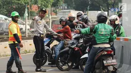Petugas mensosialisasikan uji coba pengalihan arus lalu lintas di pertigaan Jalan Pramuka Sari II, Jakarta, Jumat (21/7). Pengalihan arus lalu lintas terkait pembangunan underpass Matraman. (Liputan6.com/Helmi Fithriansyah)