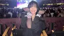 Lisa Blackpink tersenyum sambil memamerkan gelang persahabatan dengan background panggung Eras Tour. (Foto: Instagram/ lalalalisa_m)