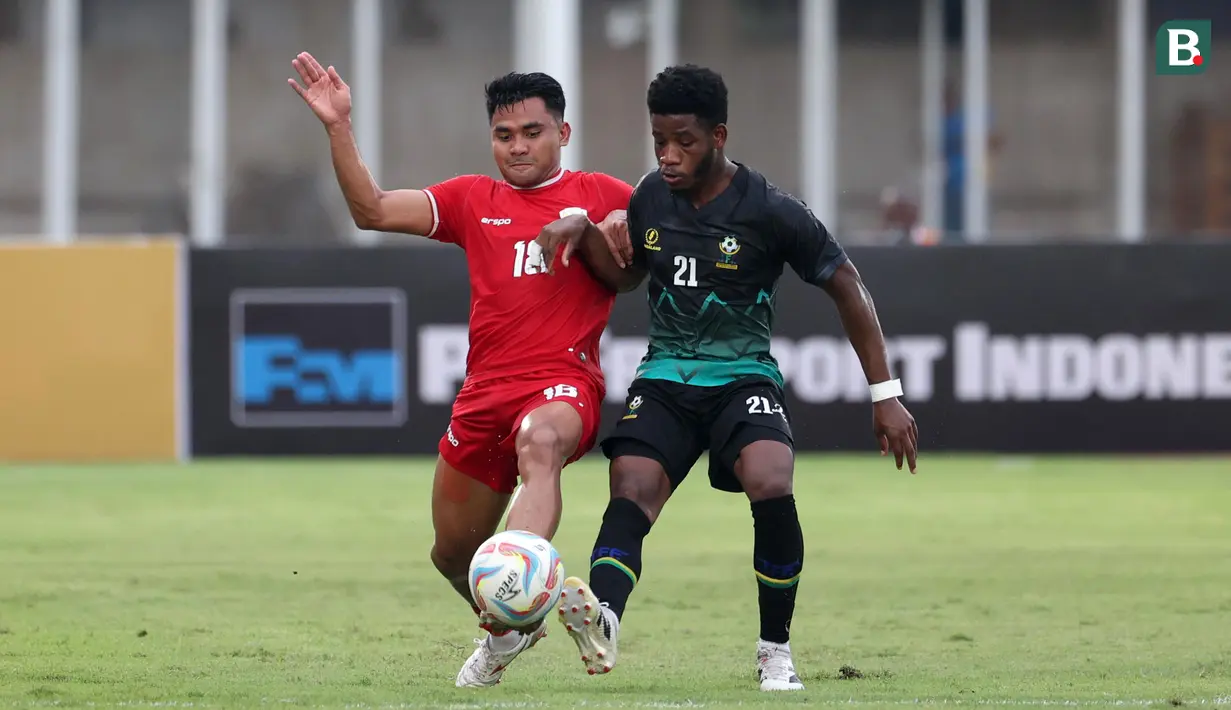 Pemain Timnas Indonesia, Asnawi Mangkualam (kiri) berebut bola dengan pemain Tanzania, Kokola Charles M'mombwa saat laga persahabatan yang berlangsung di Stadion Madya, Senayan, Jakarta, Minggu (02/06/2024). (Bola.com/Abdul Aziz)
