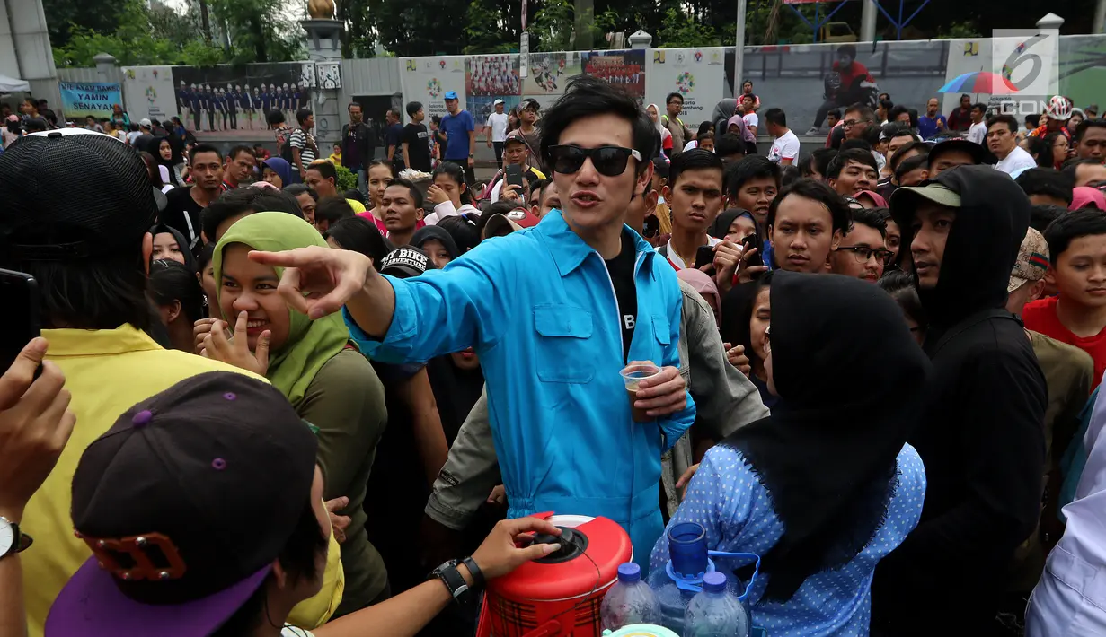 Aktor Vino G. Bastian ketika membagikan kopi gratis kepada pengunjung Car Free Day saat promo film Warkop DKI Reborn part 2 di Senayan, Jakarta, Minggu (13/08). (Liputan6.com/Fery Pradolo)