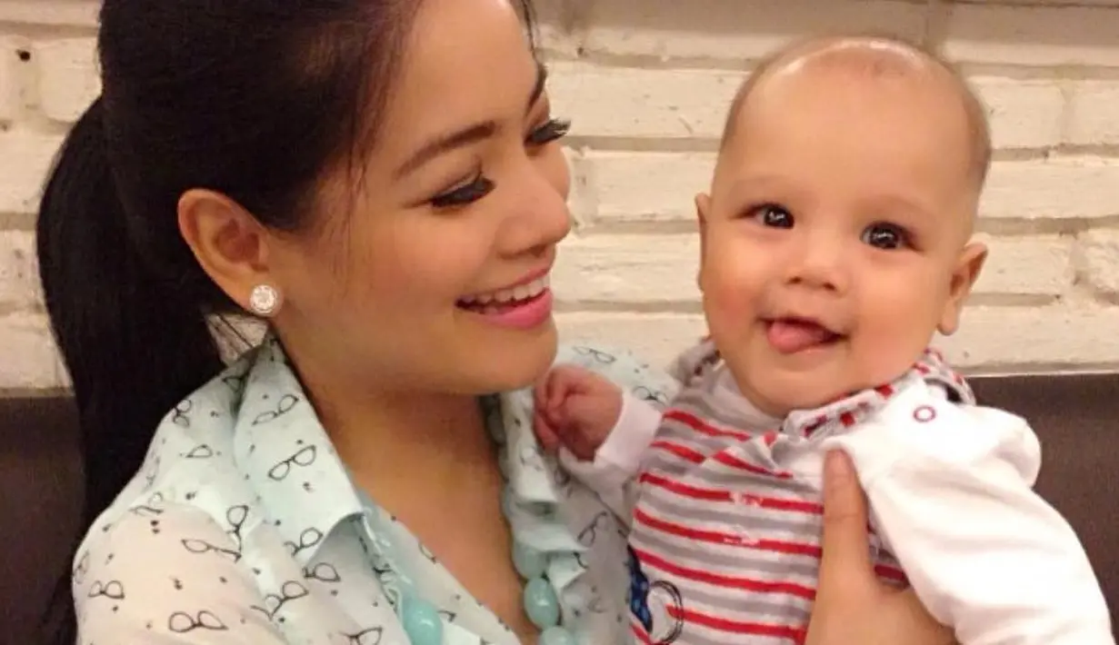 Saat menggendong baby Kai, Titi lebih sering terlihat menguncir rambutnya seperti ekor kuda. Gaya busananya juga sederhana, termasuk riasan di wajahnya yang juga tidak berlebihan. (Instagram/titi_kamall)