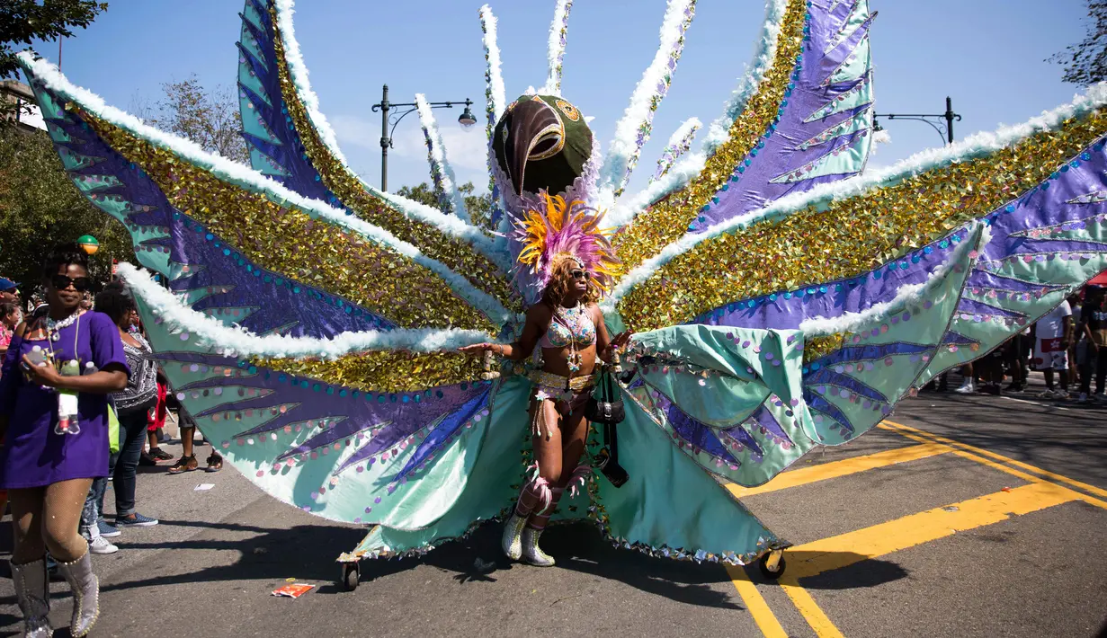 Seorang penari mengenakan kostum bulu selama ambil bagian dalam Parade West Indian Day di Brooklyn borough, New York, Senin (4/9). Parade tersebut merupakan salah satu perayaan budaya Karibia terbesar di Amerika Serikat. (AP Photo/Kevin Hagen)