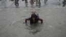 Seorang peziarah Hindu berenang selama festival Makar Sankranti di pertemuan Sungai Gangga dan Teluk Benggala di Pulau Sagar, selatan Kolkata (14/1/2022). Puluhan ribu umat Hindu di India, yang dipimpin kepala kuil dan para pertapa, mengikuti ritual suci di Sungai Gangga. (AFP/Dibyangshu Sarkar)